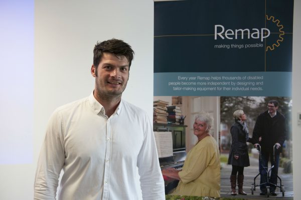 A man stands smiling in front of a Remap banner