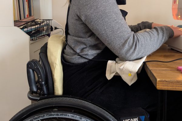 Person using sewing machine by pressing cushion in wheelchair